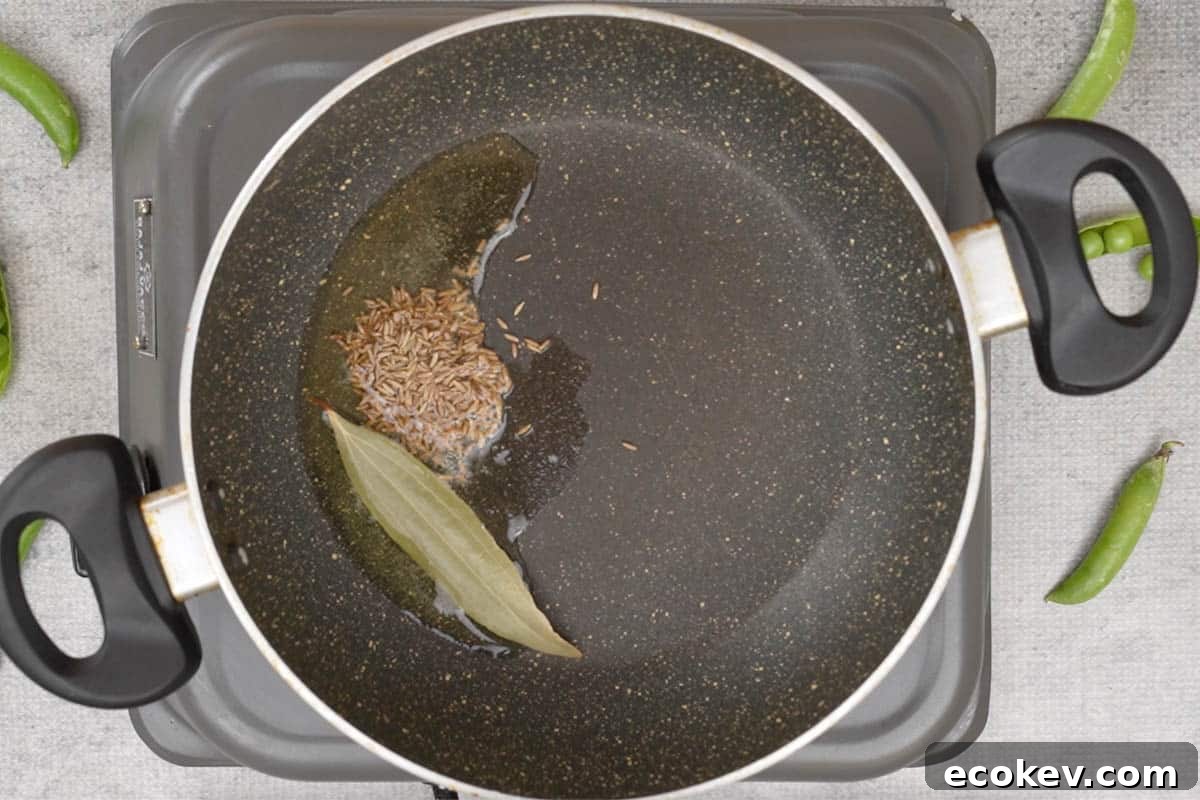 Cumin seeds and bay leaf added to the pan.