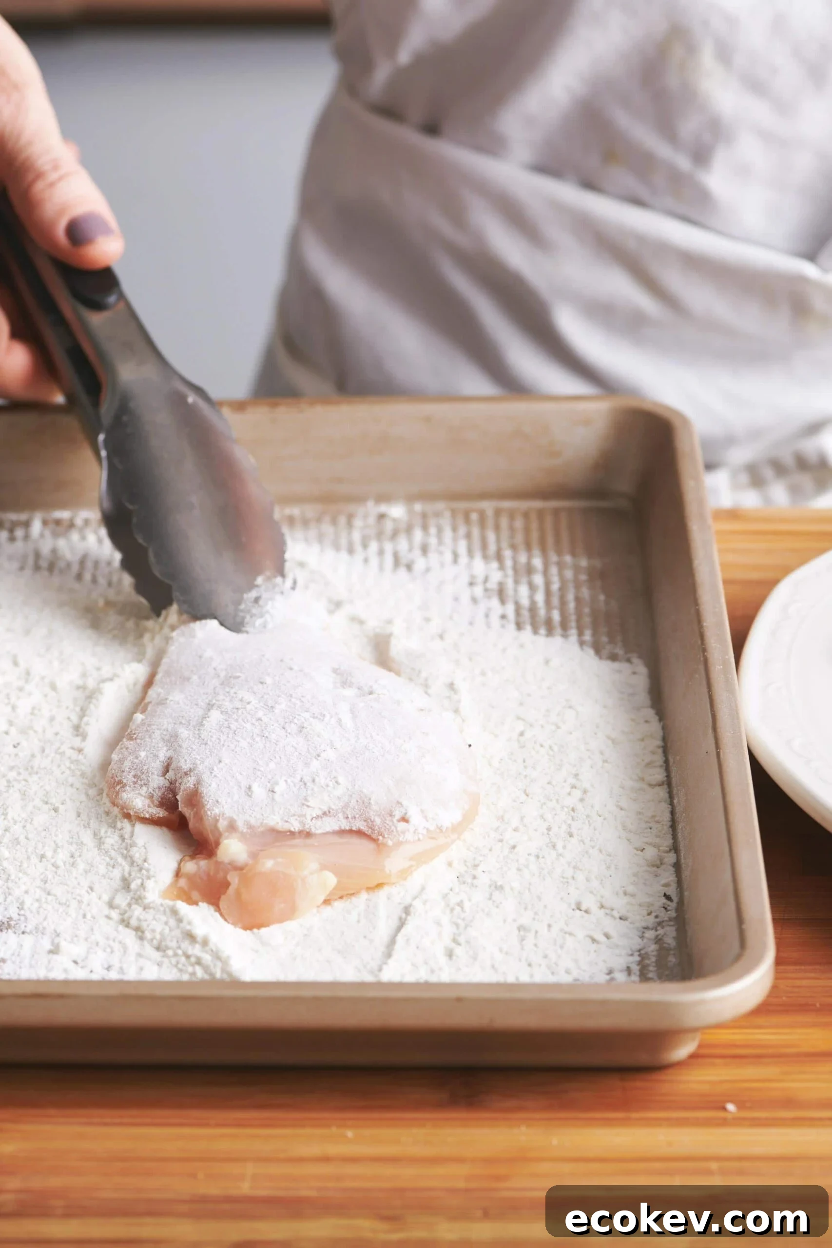 Dredging chicken in flour.