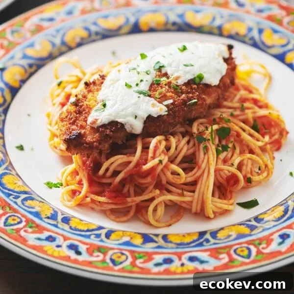 Chicken Parmigiana with spaghetti on colorful plate.