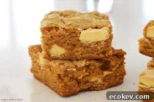 Two pieces of Caramilk Brownies on top of each other on a white bench.