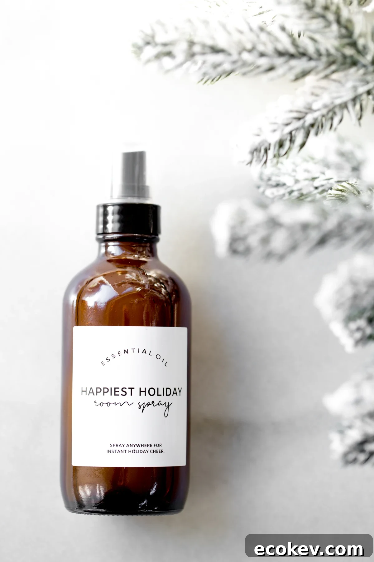 Bottle of holiday room spray on marble background with snow covered tree branches on the side