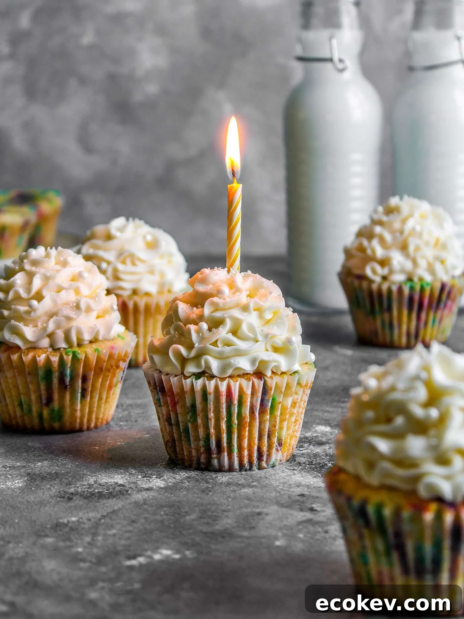 frosted funfetti cupcakes with lit candle in one cupcake