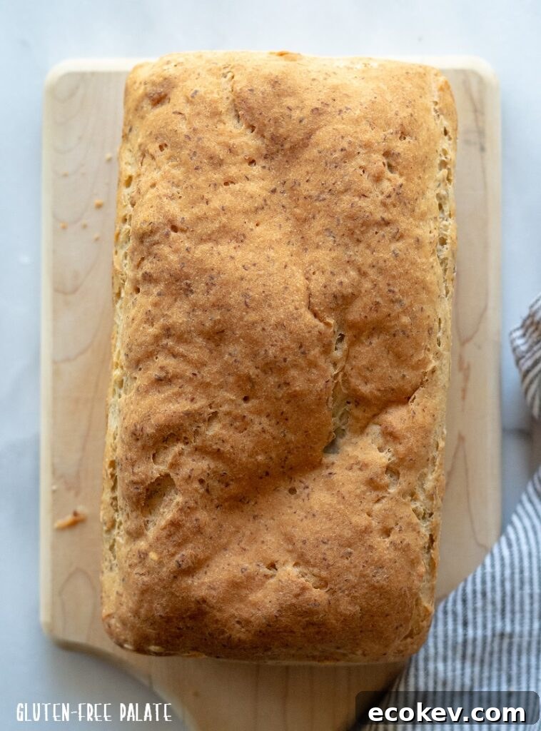 A top-down view of a whole loaf of homemade gluten-free brown bread on a cutting board.