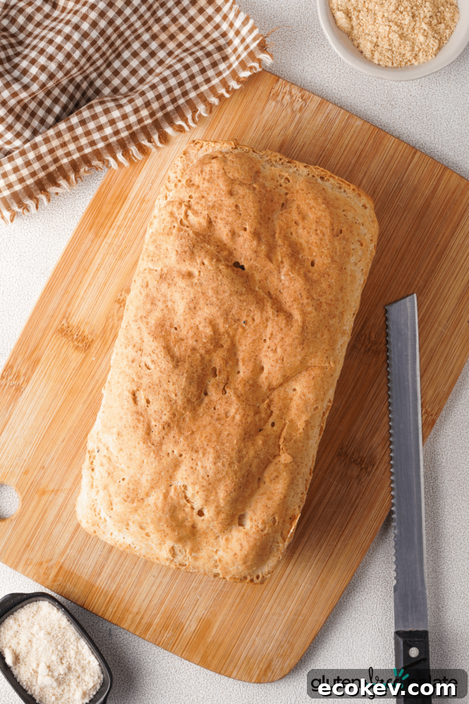 A homemade gluten-free bread loaf with a serrated bread knife on a cutting board, ready for slicing.