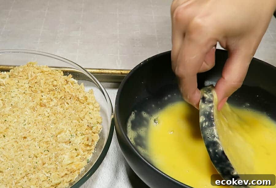 eggplant rounds being dipped in egg mixture for the crispy eggplant parmesan
