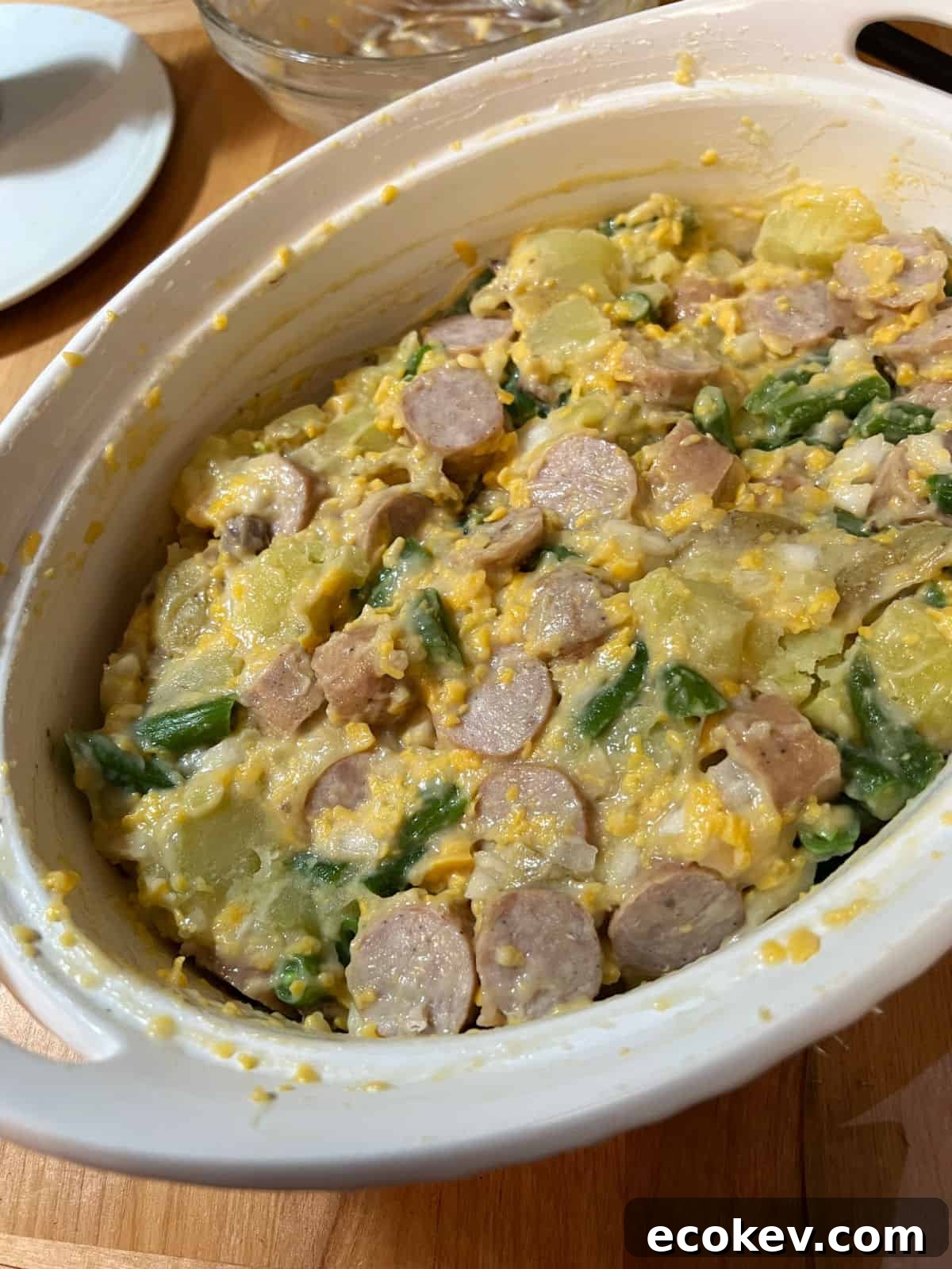 cheesy brat stew in a baking dish ready to be cooked.