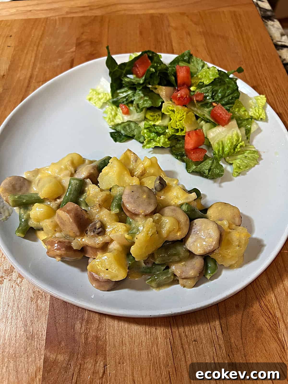 plate with a serving of cheesy brat stew with a green salad on the side.