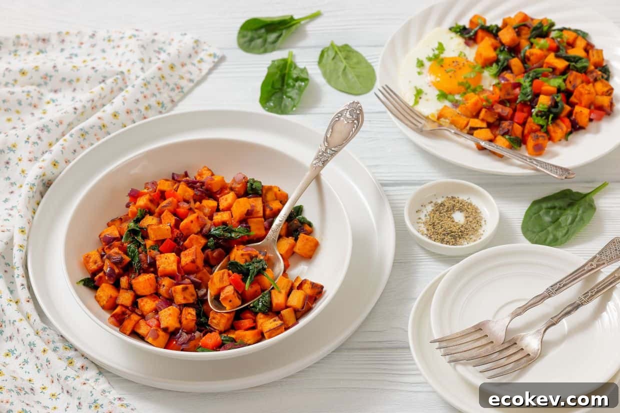 A bowl and plates of sweet potato hash with sautéed spinach and onions, served on a white table with forks, a napkin, and a small bowl of pepper.
