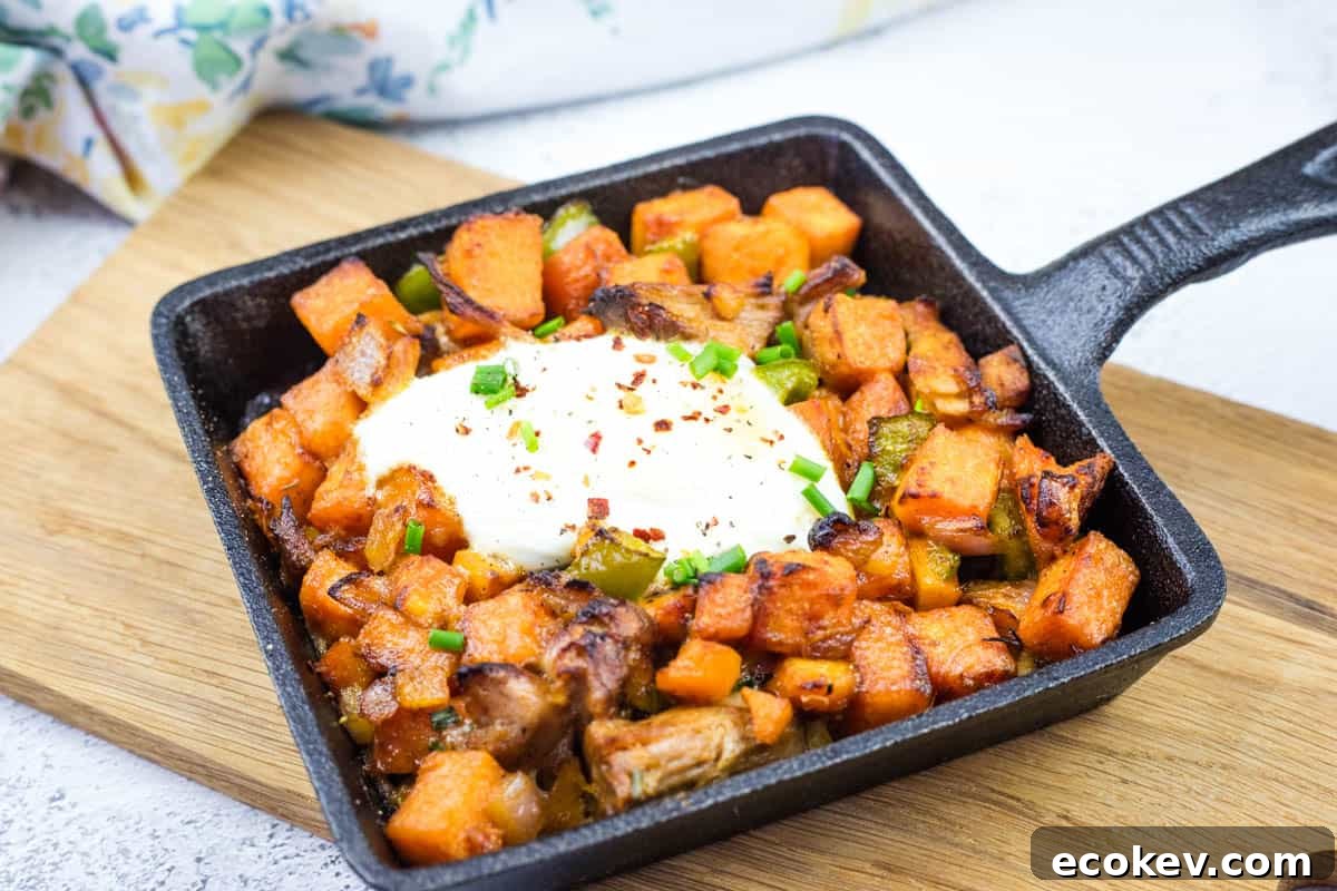 Cast iron skillet with sweet potato hash with pulled pork and garnished with chopped chives.