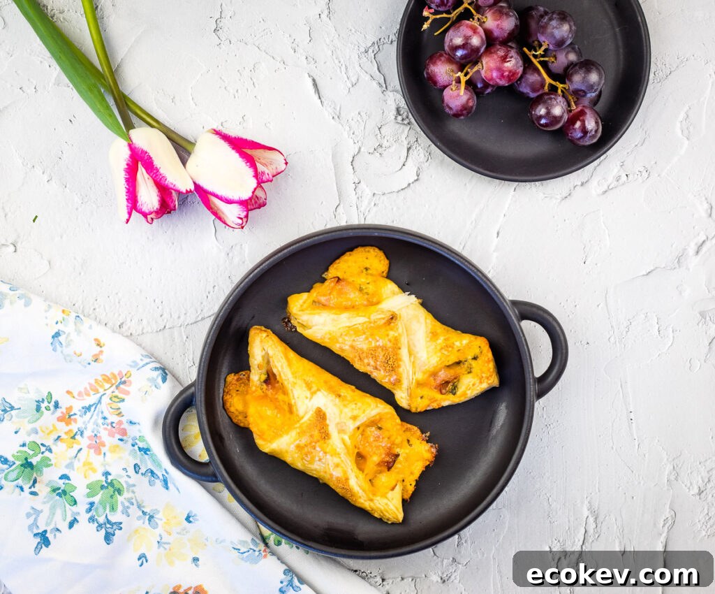 Two ham and cheese turnovers in a pan on a table.