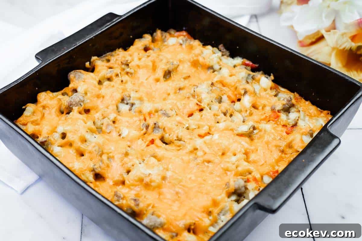 A square black baking dish filled with a baked casserole topped with melted cheese, containing visible pieces of meat and vegetables.