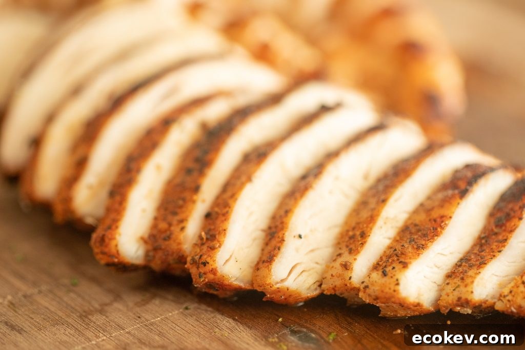 sliced grilled chicken for southwest grilled chicken salad on a wooden cutting board.