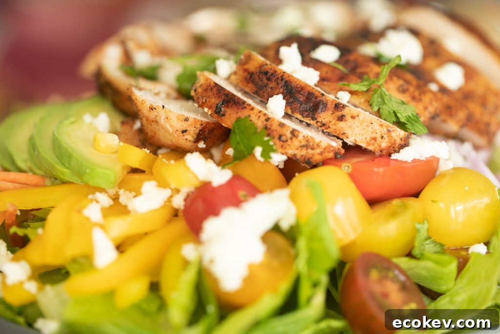 close-up image of grilled chicken on top of a bed of lettuce and vegetables.