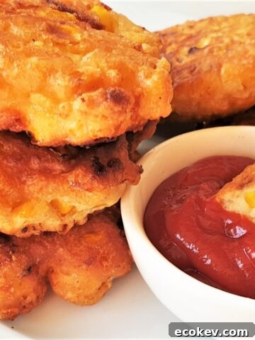 A pile of three fried crispy sweetcorn fritters with a dipping sauce.
