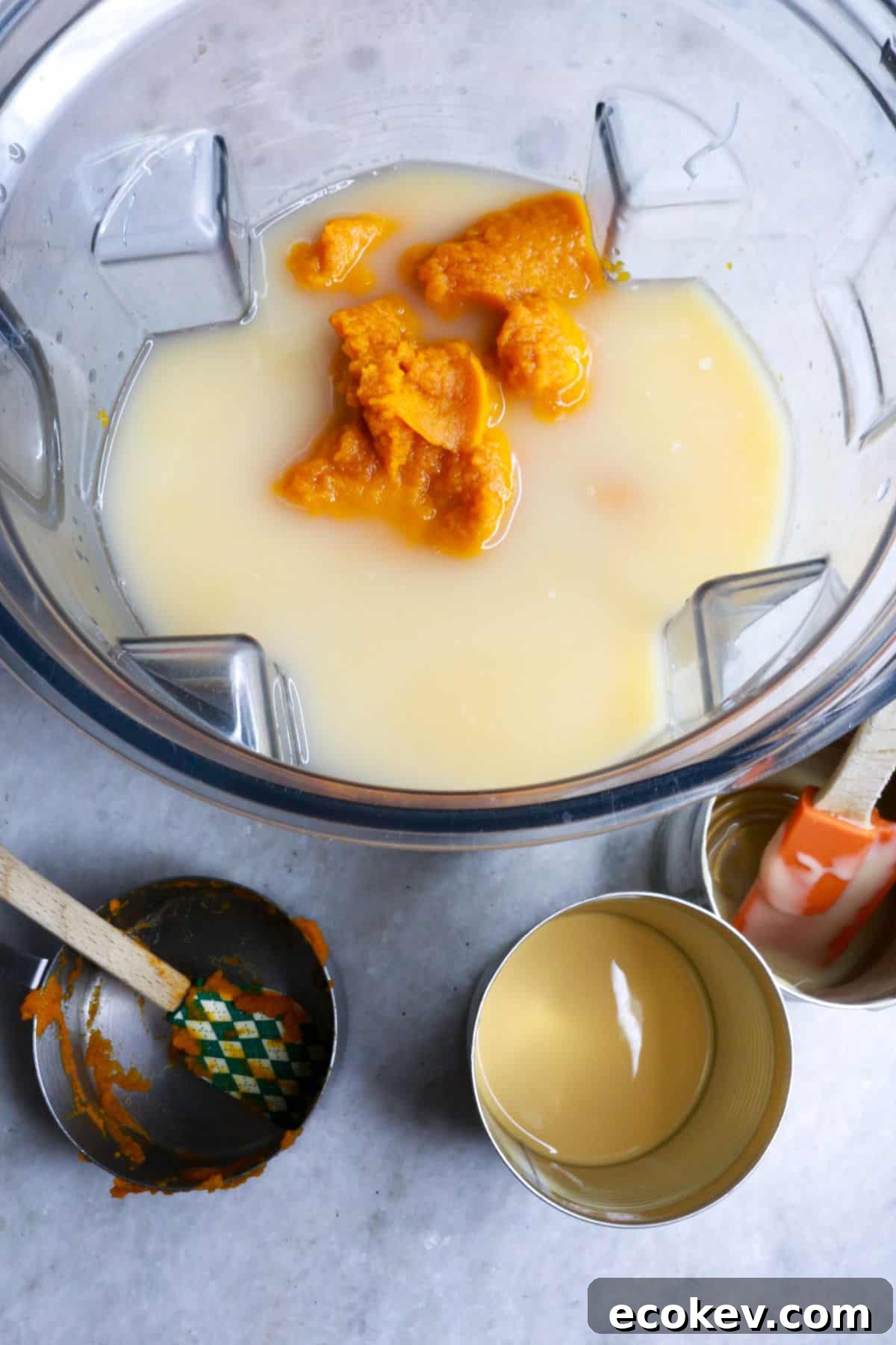 A blender with water, milk, and pumpkin puree surrounded by empty cans