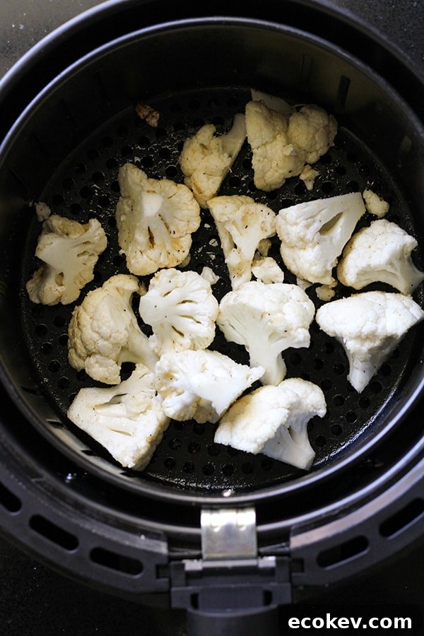 cauliflower florets in an air fryer basket.