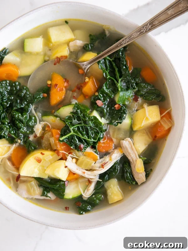 Overhead image of a white bowl filled with homemade chicken and vegetable soup.