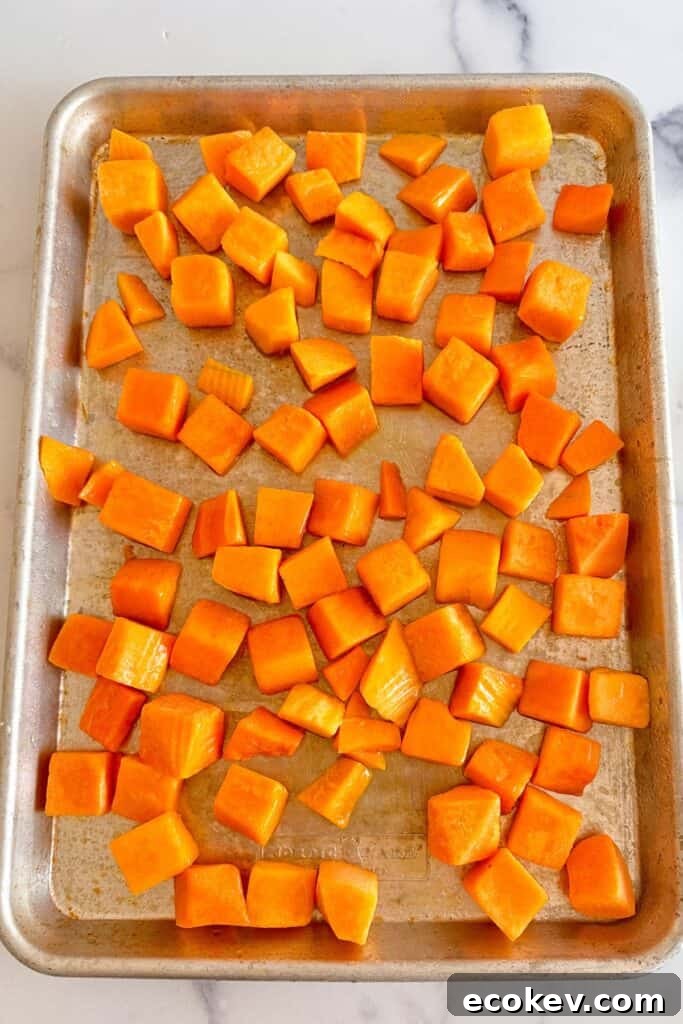 Sheet pan with diced butternut squash cubes.