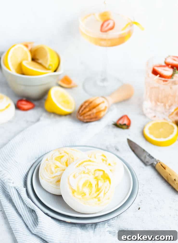 lemon meringue cookies on a plate with drinks and fresh fruit in the background