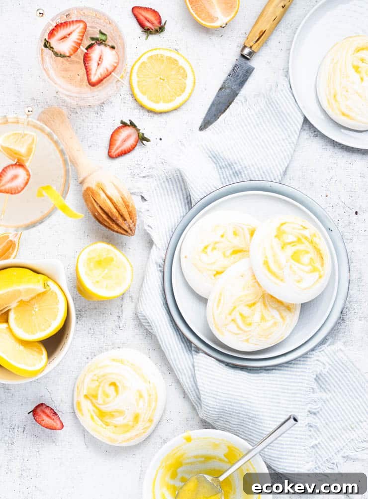 overhead view of meringue cookies on plates with strawberries and lemons around them