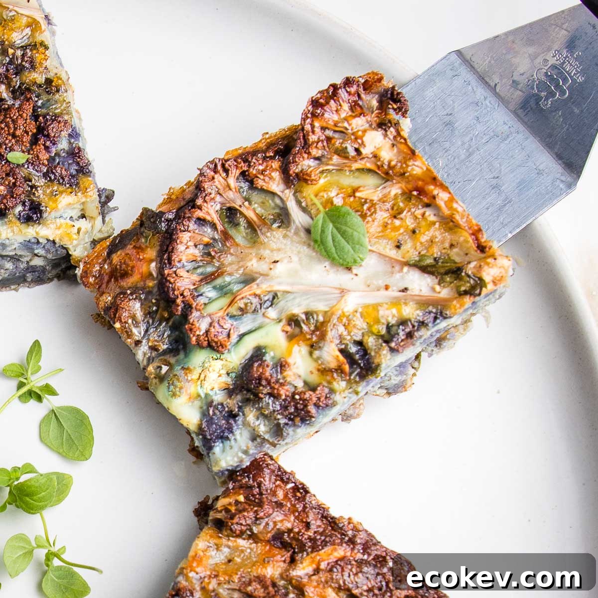 Slice of cauliflower kugel sprinkled with fresh herbs.