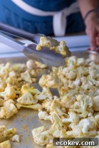 Cauliflower florets sprinkled with spices on a baking sheet.