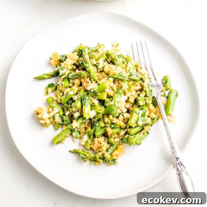 Asparagus with cauliflower rice on a plate with a fork.
