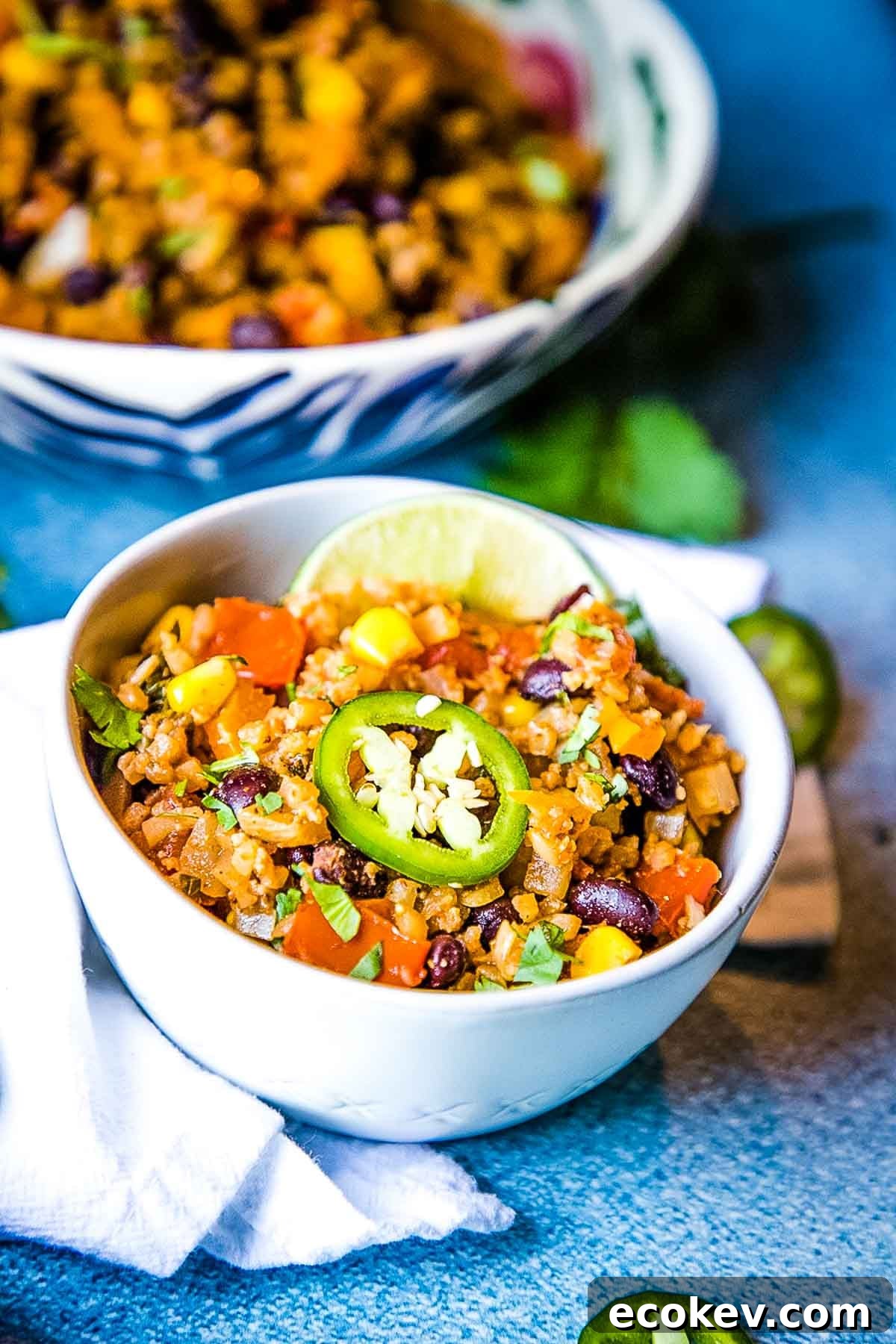 Bowl of cauliflower rice with black beans, corn, tomatoes and jalapeno.