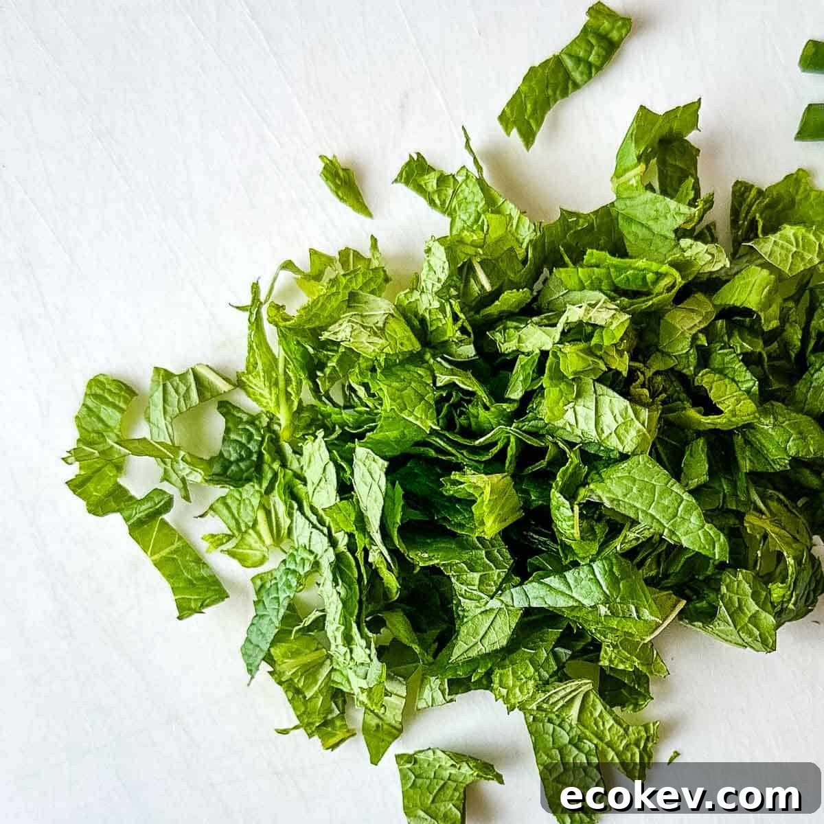 Chopped mint on a white cutting board.
