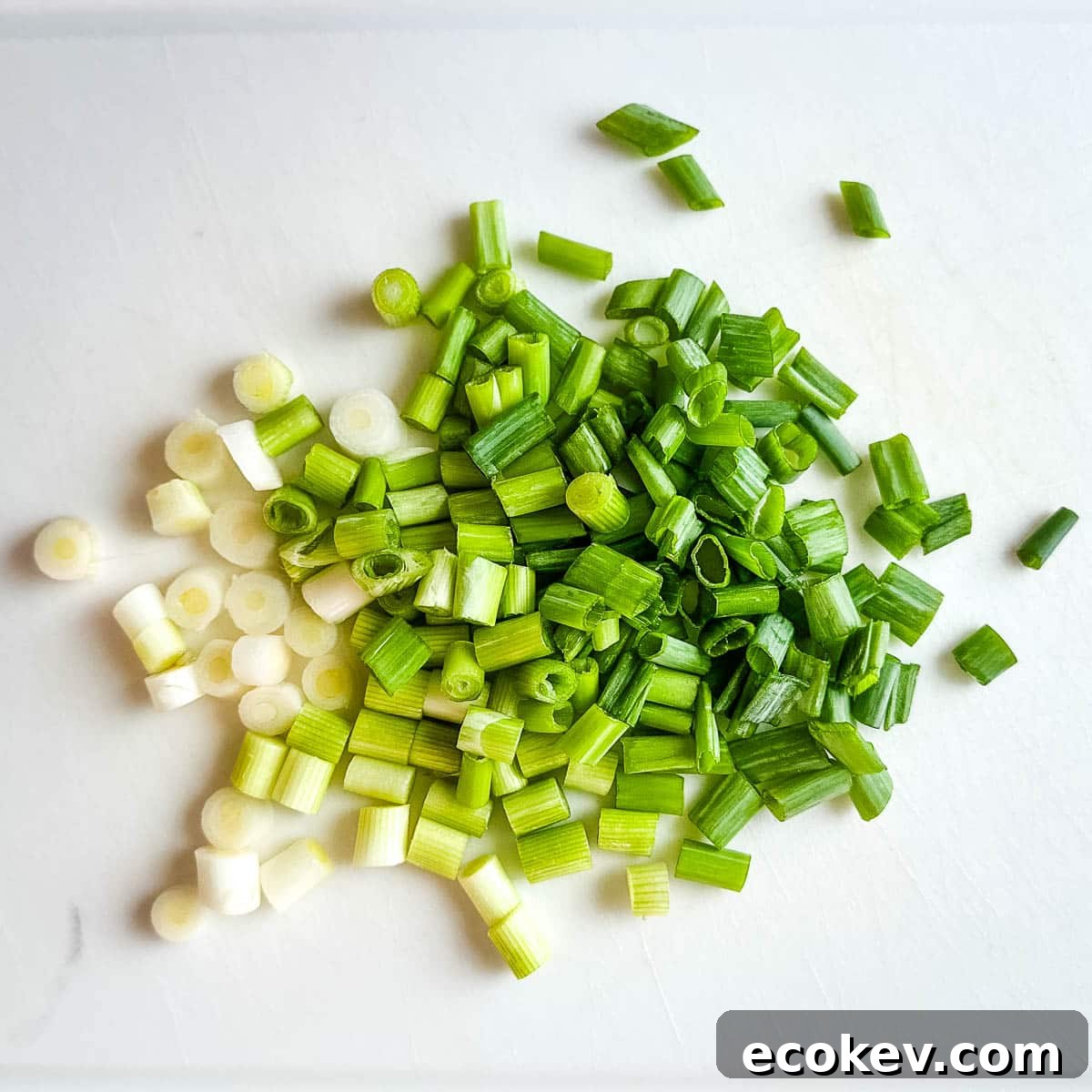 Chopped scallions on a white cutting board.