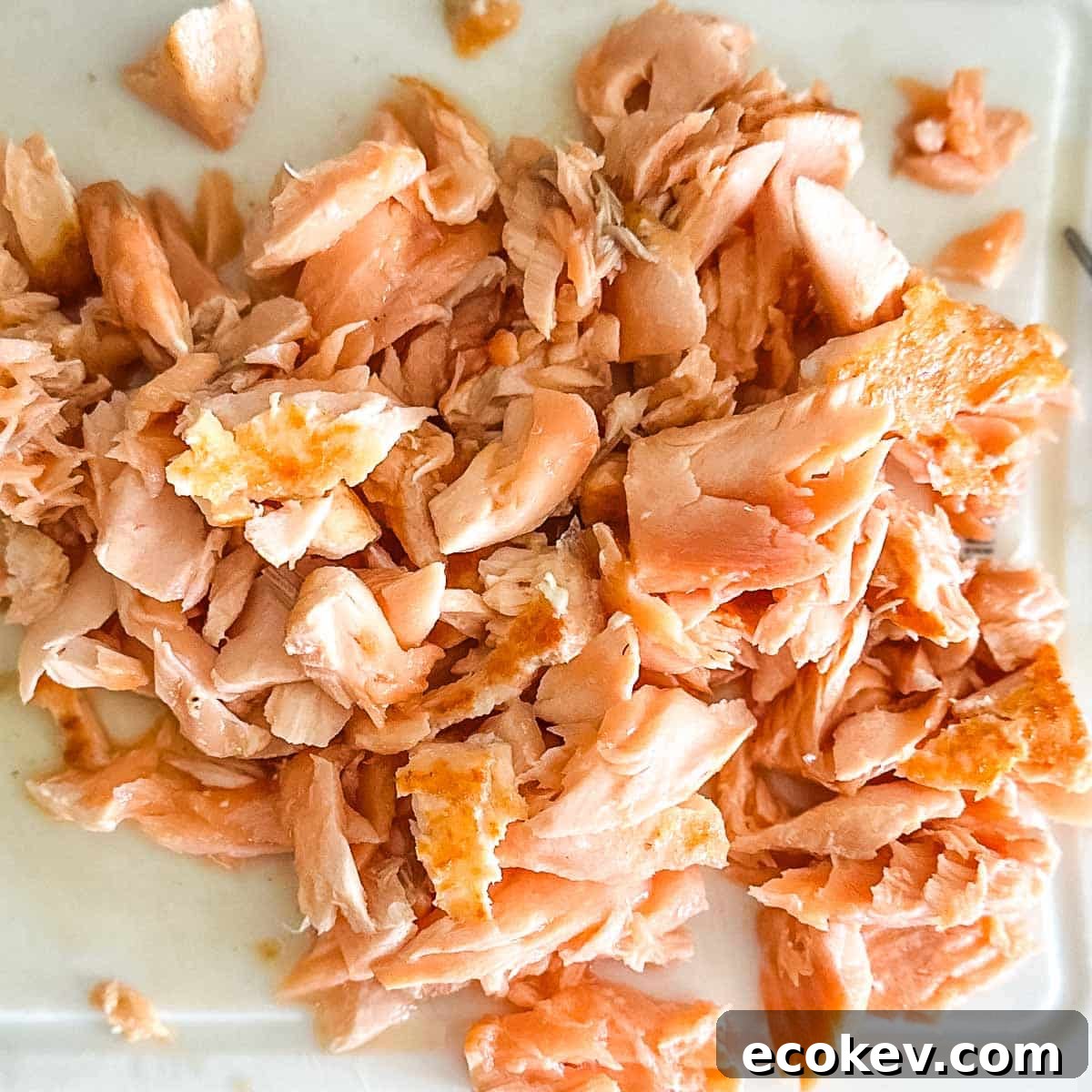 Flaked salmon on a white cutting board.