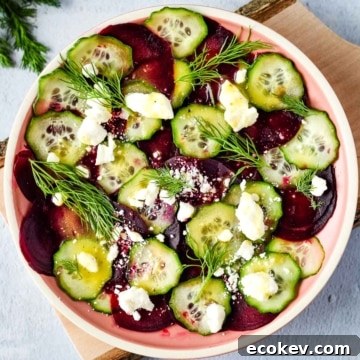 beet cucumber salad with feta and dill in a pink dish.