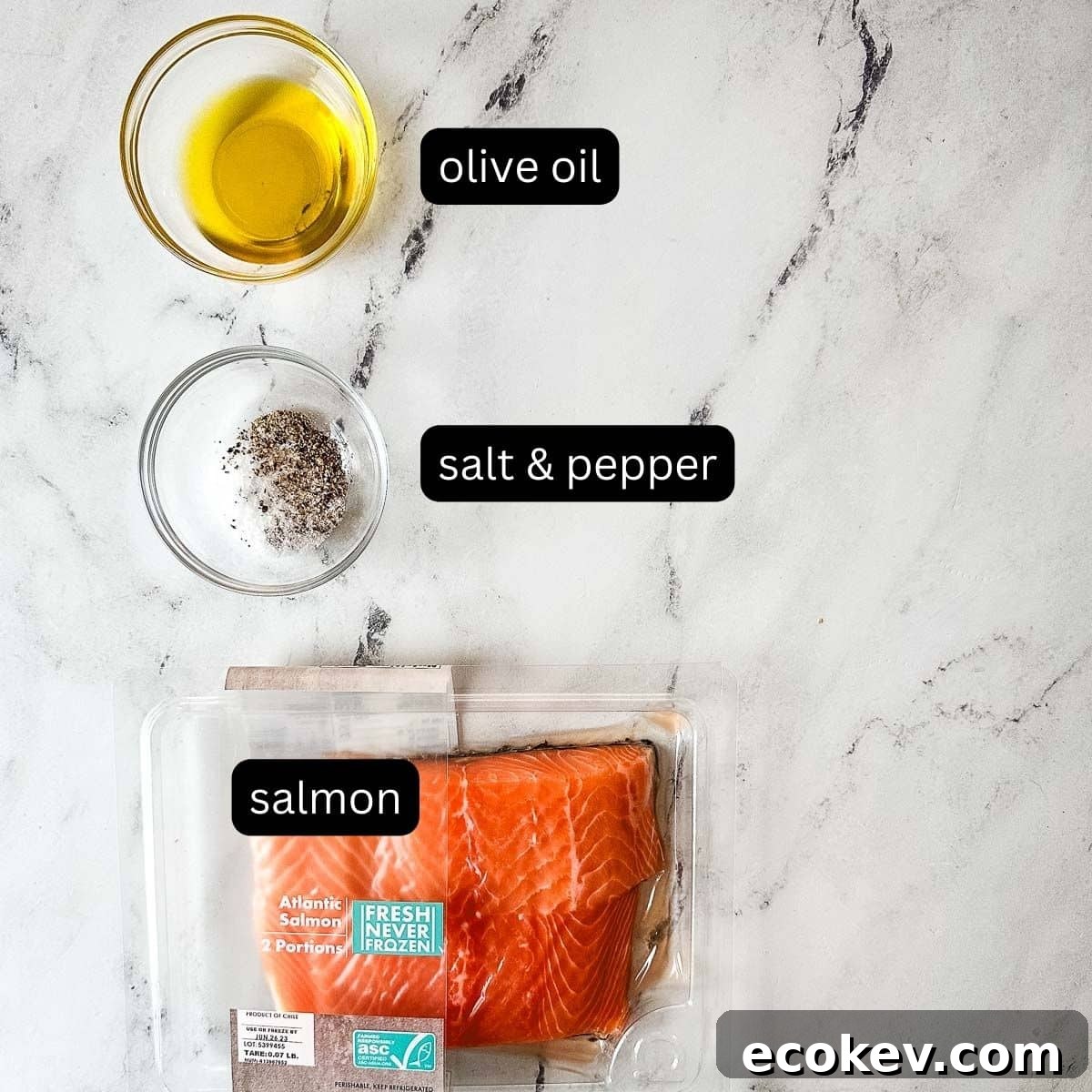 Labeled ingredients for pan-seared salmon on a white marble counter.