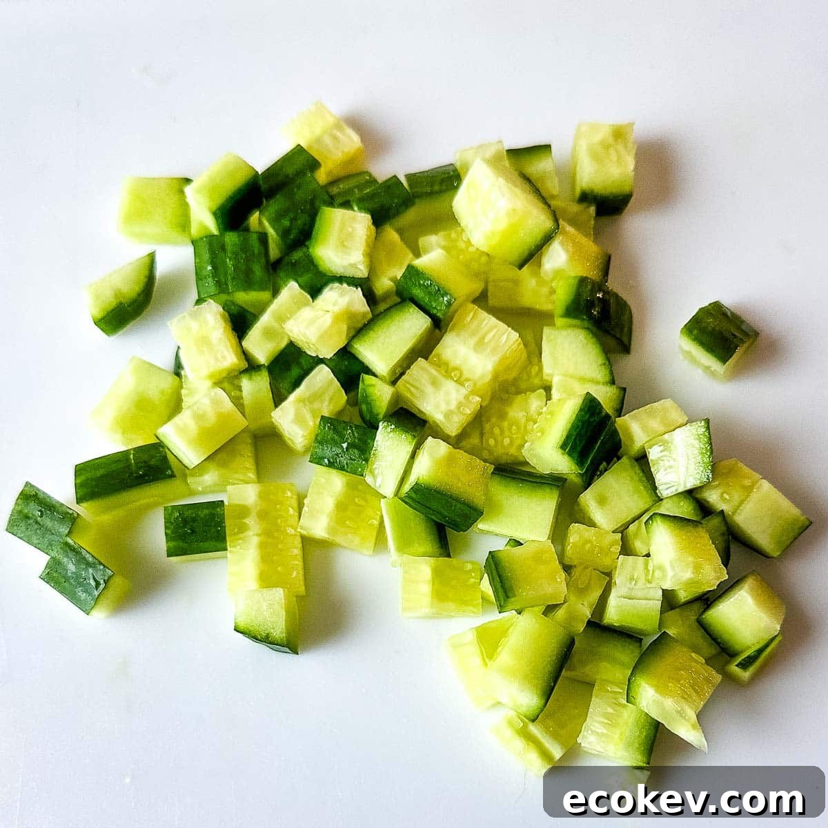 Diced cucumber on a white cutting board.