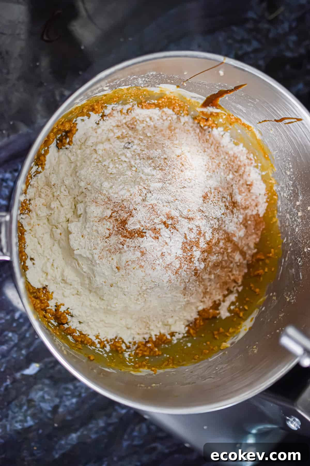 The dry ingredients are added to the bowl with the wet ingredients in a stand mixer.