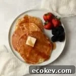 Single serve pancakes on a plate with maple syrup and berries.