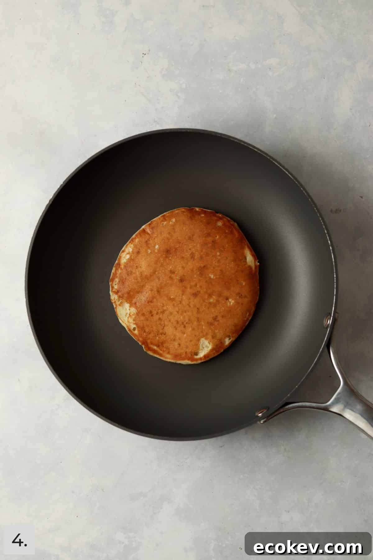 One pancake in nonstick skillet with golden brown coloring.