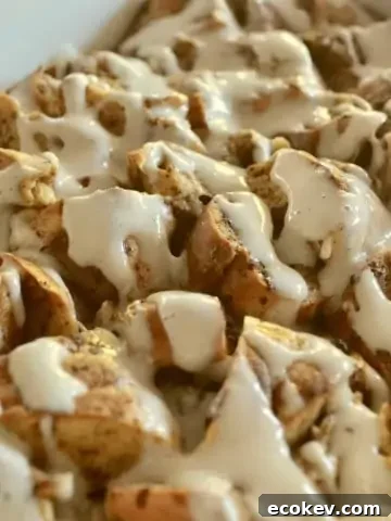 overnight bagel French toast in a white baking dish with maple cream cheese glaze