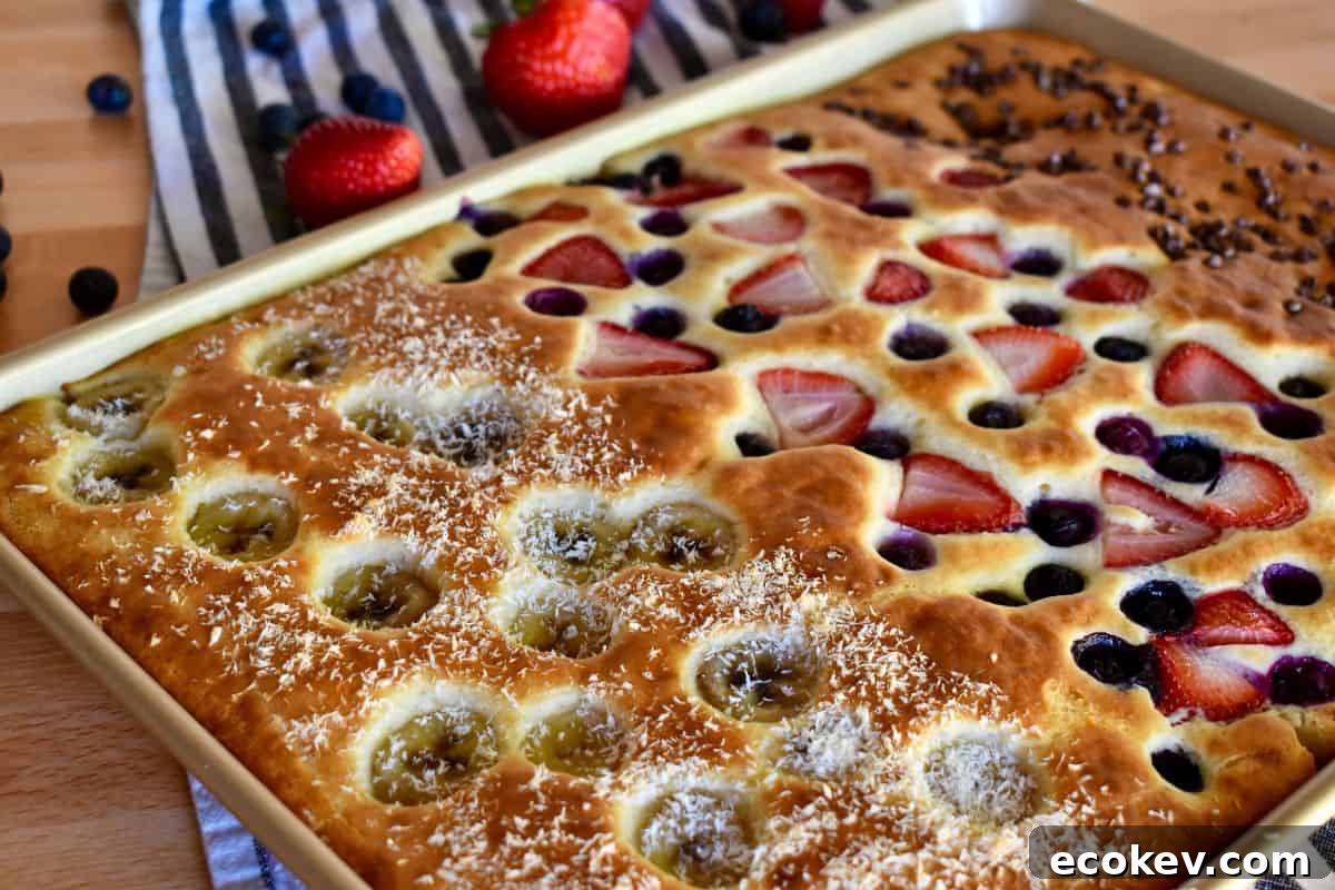 Sheet Pan Pancakes from Mix in a baking pan with berries, bananas, and chocolate chips on top. 