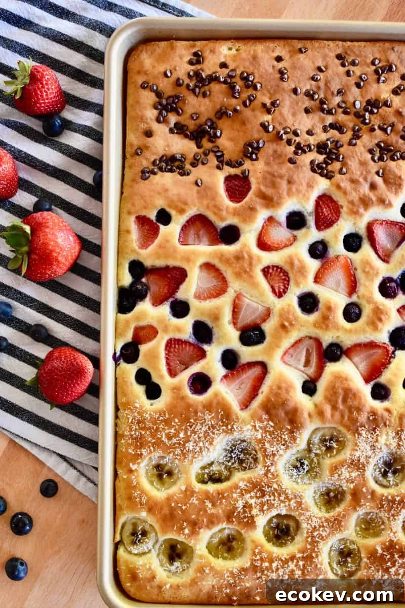 Sheet Pan Pancakes from mix with berries, chocolate chips, bananas, and shredded coconut on top. 