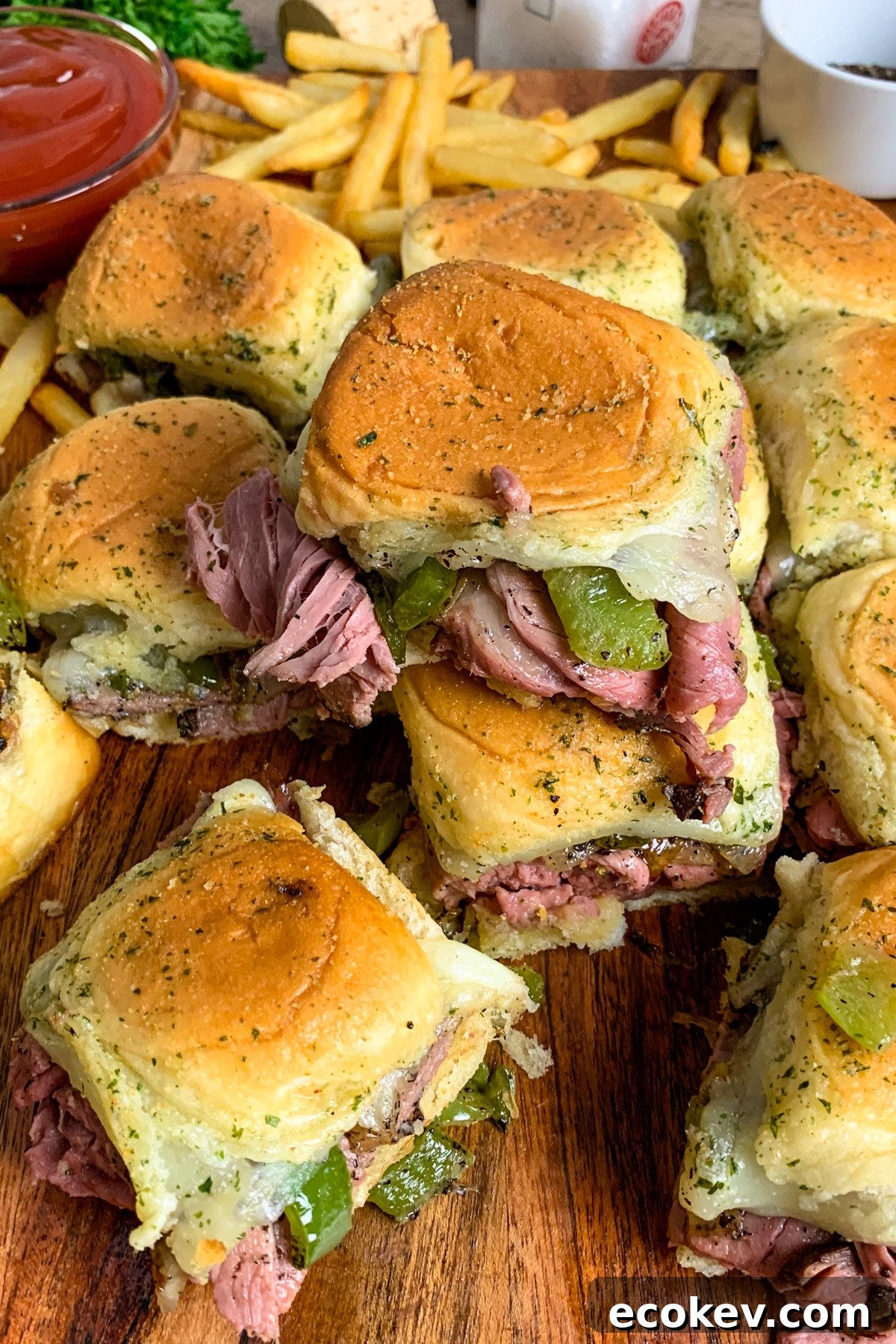 Cheesesteak sliders made with roast beef, onions, and green peppers stacked on top of each other.