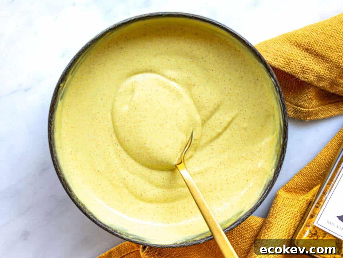 Step 1 Greek yogurt dressing with curry and mustard being whisked until smooth.