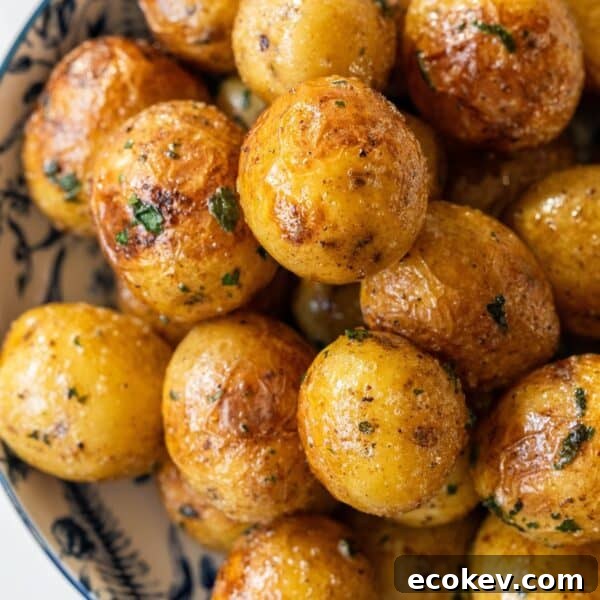 A bowl filled with golden-brown butter poached potatoes, seasoned with herbs and spices.