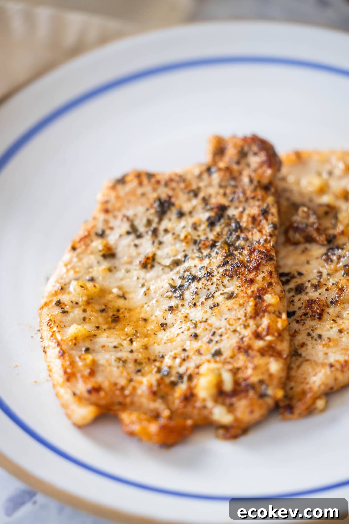 A plate of pan-seared pork schnitzel served on a white surface, with hints of garlic elevating the aroma.