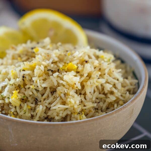 A bowl of Baked Lemon Rice garnished with herbs and lemon zest, with two lemon wedges in the background.
