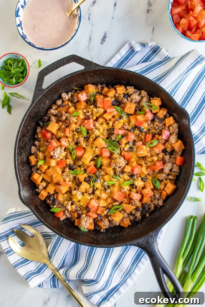 Sweet potatoes and turkey skillet with black beans covered with melted cheddar cheese and topped with diced tomatoes and sliced green onions.