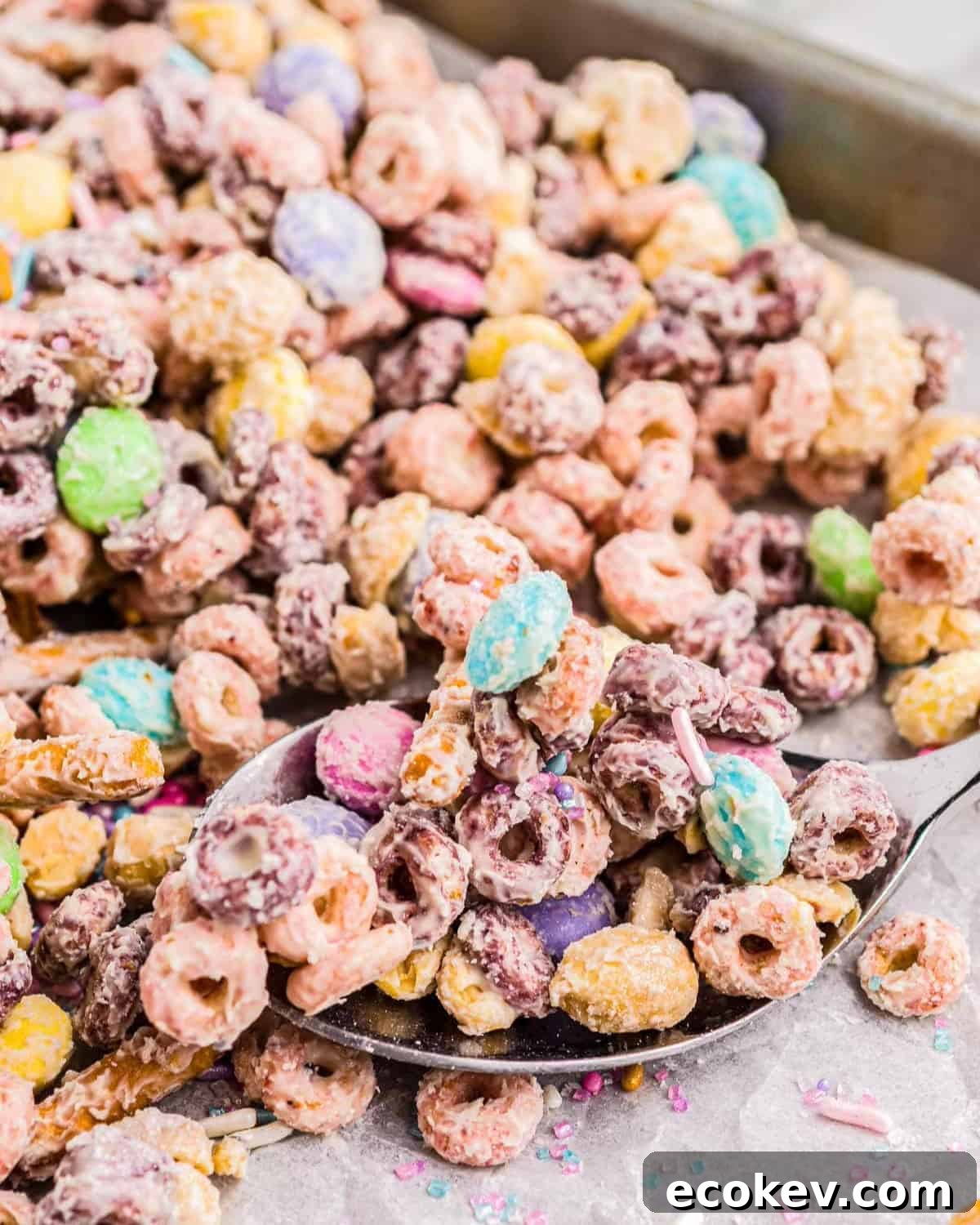 A spoon scooping up Easter snack mix from a tray.
