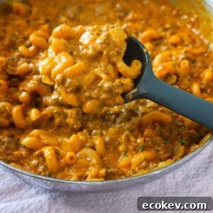 Creamy yellow - orange hamburger helper noodles being scooped with a spoon.