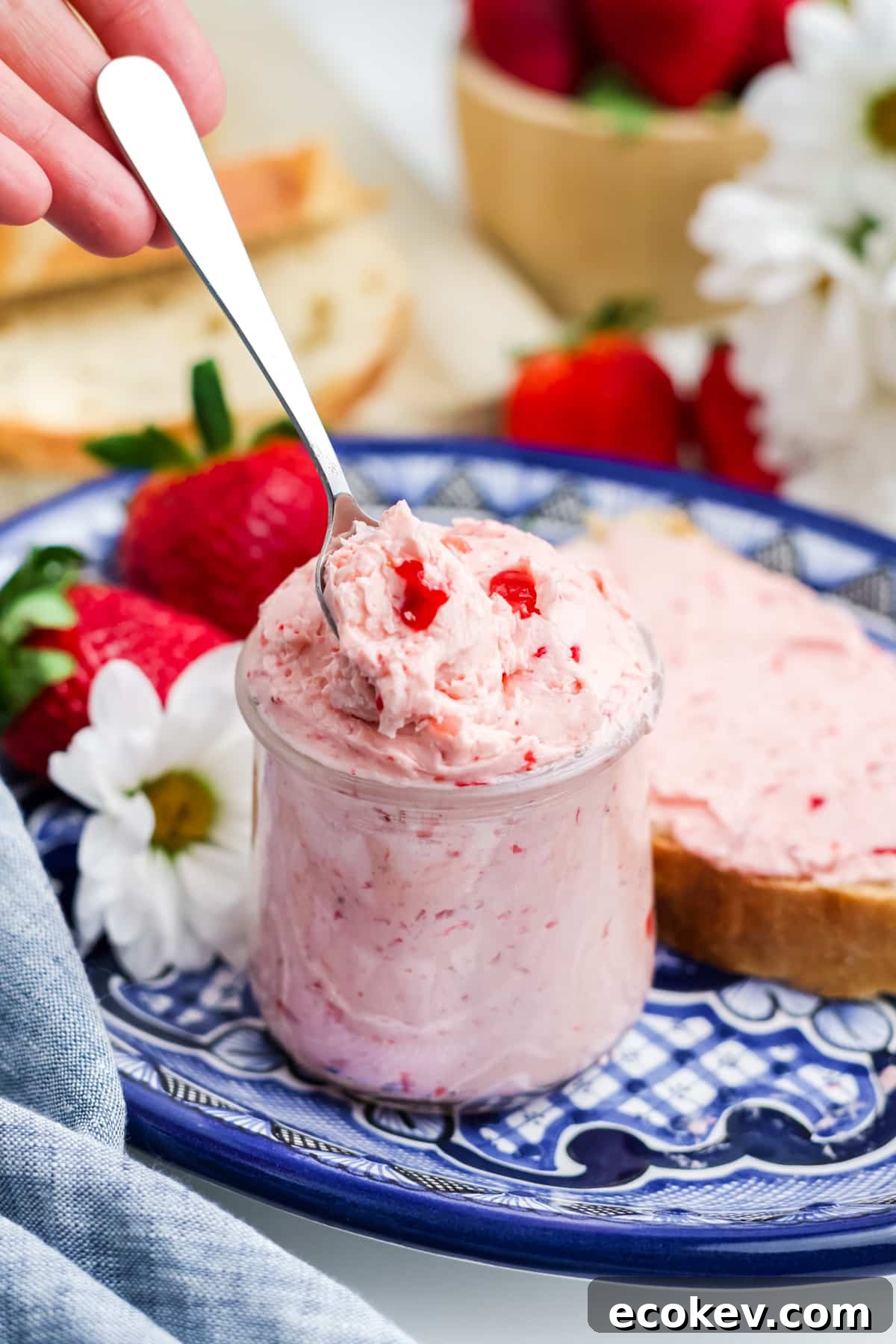 Strawberry butter in a jar on a white and blue plate. 