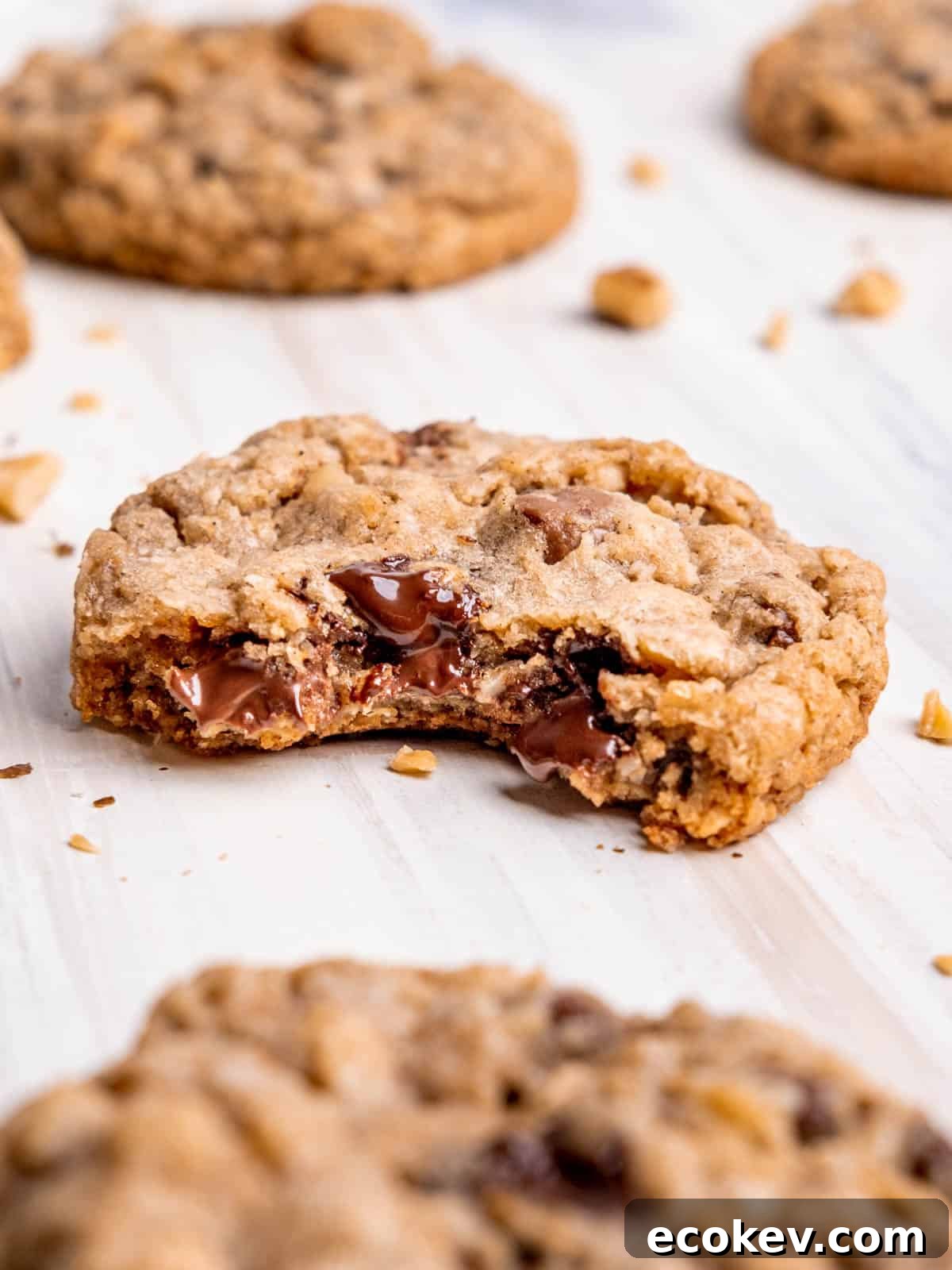 A cowboy cookie laying on the counter with a bite taken out of it, revealing melted chocolate chips inside.